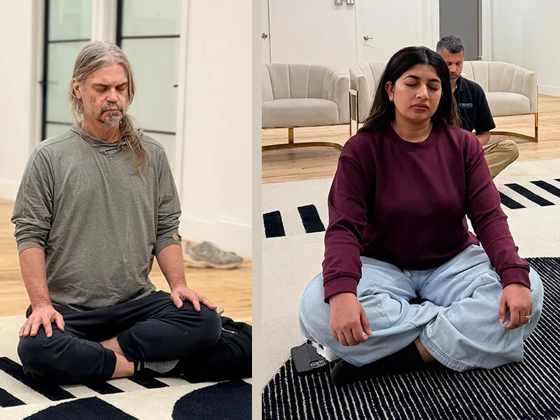 Two participants meditating with eyes closed and hands resting on their knees at a Meditate With A Monk session in New York