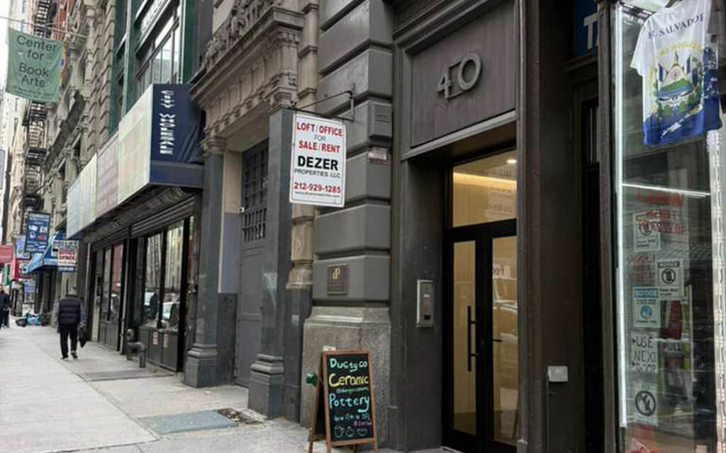 The street entrance to 40 W 27th Street in Manhattan, a grey stone building front with the number 40 above the glass door