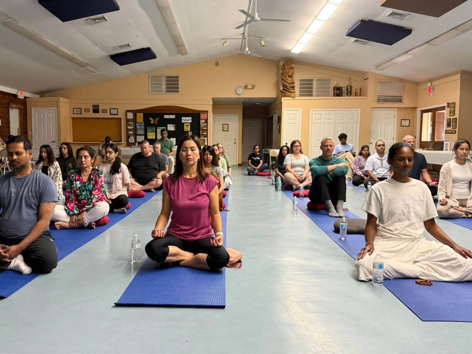 Retreat participants meditating on blue mats in the hall at the East Brunswick day-long meditation retreat