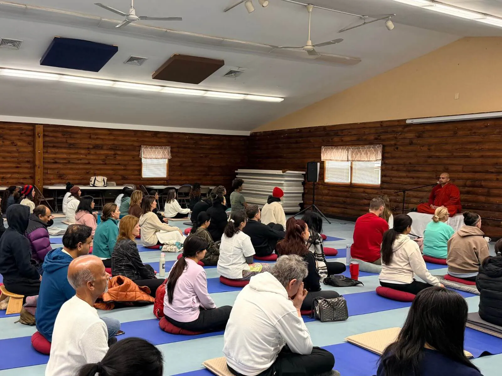 Participants seated in the log-cabin hall as a Buddhist monk leads breathing meditation, East Brunswick NJ